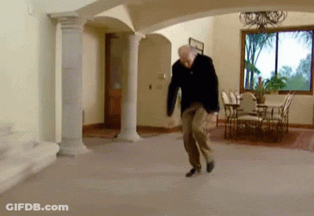 A Man Is Dancing In A Living Room With Columns And A Dining Table . GIF