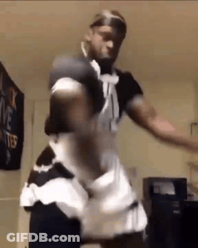 A Man Is Dancing In A Maid Costume In A Room . GIF