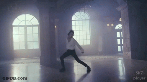 A Man Is Dancing In A Room With A Skz Player Logo GIF