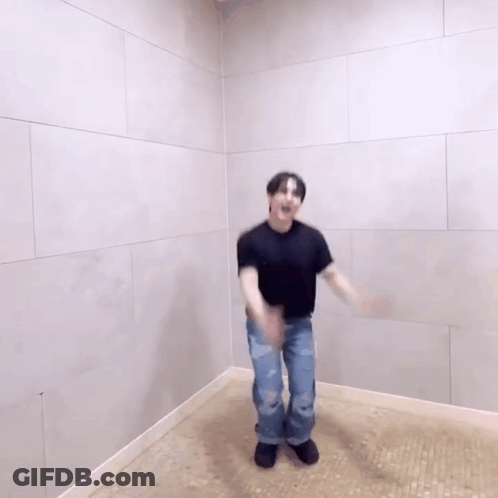 A Man Is Dancing In A Room With A White Wall . GIF