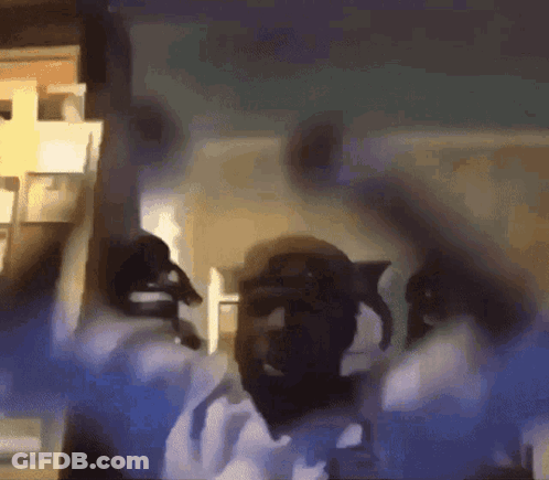 A Man Is Dancing In A Room With His Arms In The Air GIF