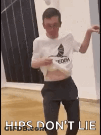 A Man Is Dancing In A Room With The Words `` Hips Do N't Lie '' Written On The Bottom . GIF