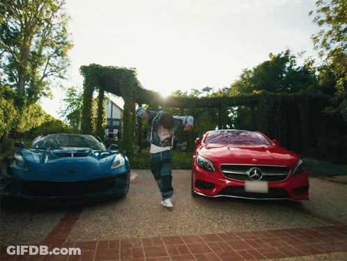 A Man Is Dancing In Front Of A Blue Car And A Red Mercedes GIF