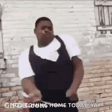 A Man Is Dancing In Front Of A Brick Wall With The Words `` You Coming Home Today ! Yay '' Written On It . GIF