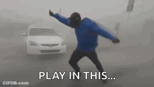 A Man Is Dancing In Front Of A Car In A Foggy Street . GIF