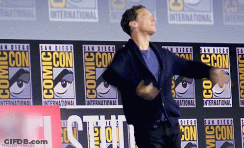 A Man Is Dancing In Front Of A Comic Con Banner GIF