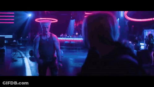 A Man Is Dancing In Front Of A Crowd In A Club With Purple And Blue Lights . GIF