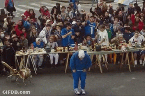 A Man Is Dancing In Front Of A Crowd Of People . GIF