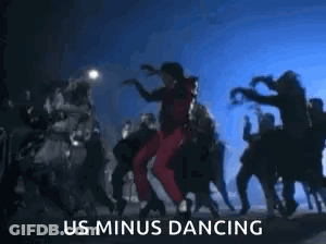 A Man Is Dancing In Front Of A Crowd Of People With The Words `` Us Minus Dancing '' Written Below Him . GIF