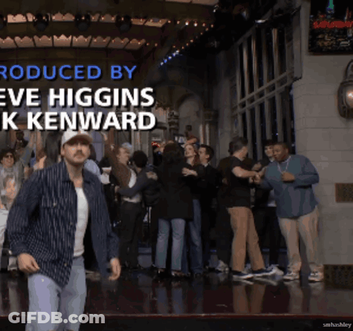 A Man Is Dancing In Front Of A Crowd With The Words Produced By Eve Higgins K Kenward GIF