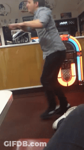 A Man Is Dancing In Front Of A Jukebox That Has The Word News On It GIF