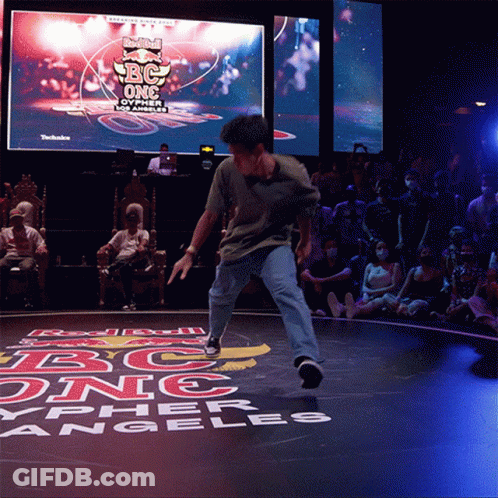 A Man Is Dancing In Front Of A Large Screen That Says Red Bull Bc One GIF