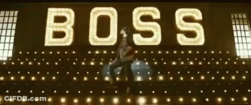A Man Is Dancing In Front Of A Large Sign That Says Boss GIF