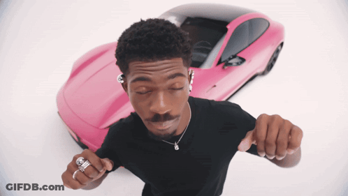 A Man Is Dancing In Front Of A Pink Sports Car GIF