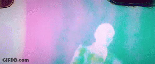 A Man Is Dancing In Front Of A Pink Wall In A Room . GIF