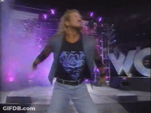 A Man Is Dancing In Front Of A Purple Sign That Says Wwe GIF