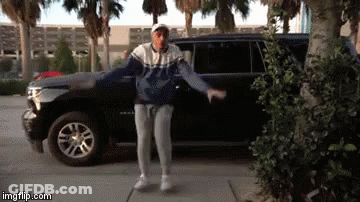 A Man Is Dancing In Front Of A Suv . GIF