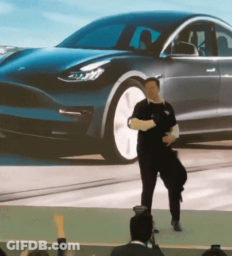 A Man Is Dancing In Front Of A Tesla Model 3 Car GIF