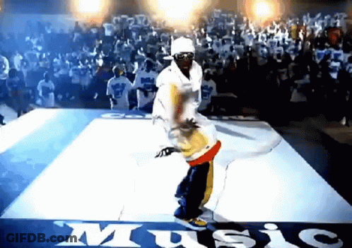 A Man Is Dancing On A Dance Floor In Front Of A Crowd With The Word Music Written On The Floor GIF