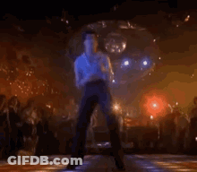 A Man Is Dancing On A Disco Floor In Front Of A Crowd . GIF