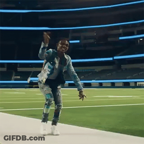 A Man Is Dancing On A Football Field . GIF