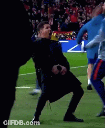 A Man Is Dancing On A Soccer Field While Holding A Microphone In His Hand . GIF