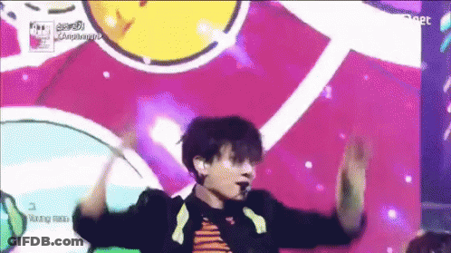 A Man Is Dancing On A Stage In Front Of A Colorful Background With The Word Compliments Written On It GIF
