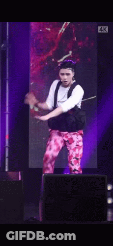 A Man Is Dancing On A Stage In Front Of A Large Screen . GIF