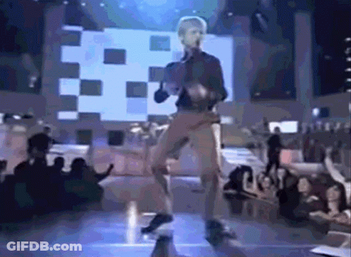 A Man Is Dancing On A Stage With A Crowd Watching GIF