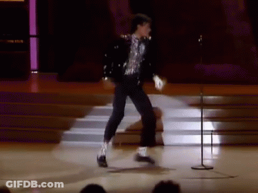 A Man Is Dancing On A Stage With A Microphone GIF