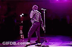 A Man Is Dancing On A Stage With A Microphone In Front Of Him GIF