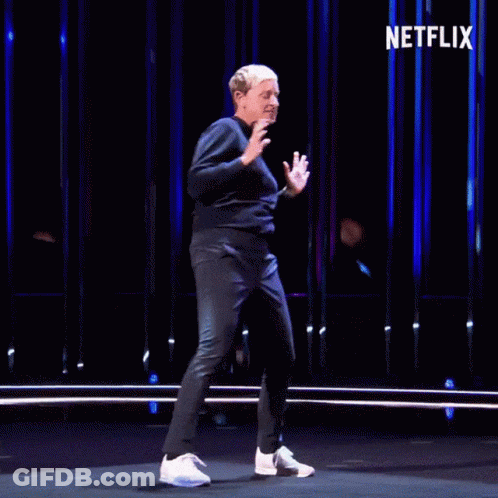 A Man Is Dancing On A Stage With The Netflix Logo In The Background GIF