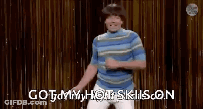 A Man Is Dancing On A Stage With The Words `` Got My Hot Skills On '' Behind Him . GIF