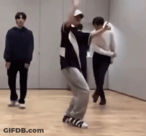 A Man Is Dancing On A Wooden Floor In A Room While Two Other Men Watch . GIF