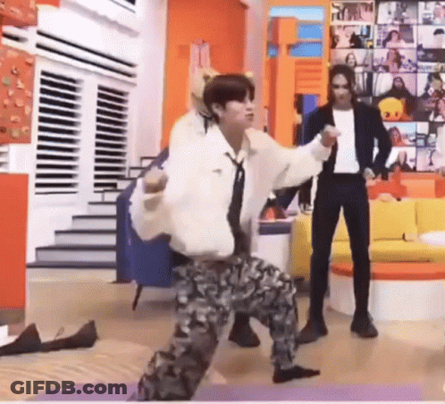 A Man Is Dancing On A Yoga Mat In A Living Room While A Man Stands Behind Him . GIF