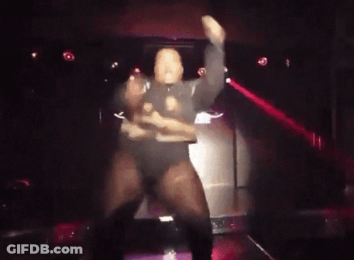 A Man Is Dancing On Stage In A Dark Room GIF