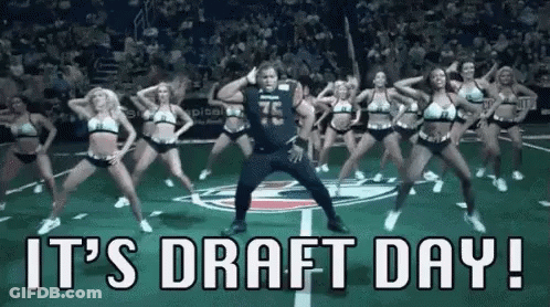 A Man Is Dancing With A Group Of Cheerleaders On A Field . GIF