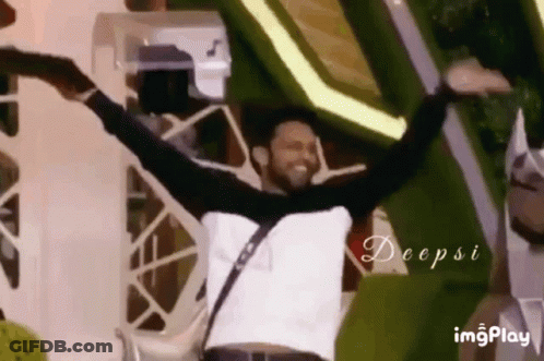A Man Is Dancing With His Arms Outstretched In Front Of A Crowd . GIF