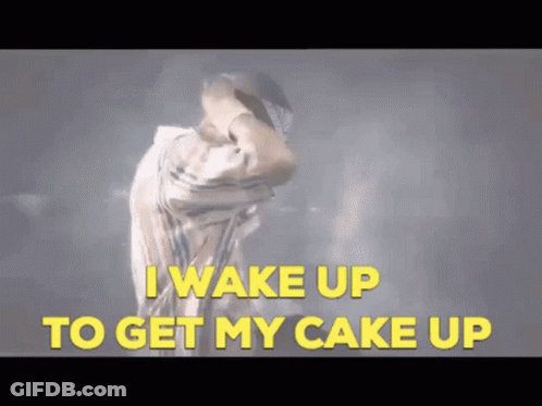 A Man Is Dancing With The Words " I Wake Up To Get My Cake Up " Behind Him GIF