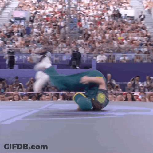 A Man Is Doing A Handstand In Front Of A Crowd That Is Watching GIF