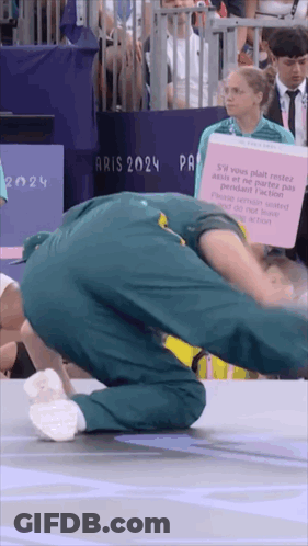 A Man Is Doing A Handstand In Front Of A Sign That Says " Aris 2024 " GIF