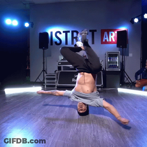 A Man Is Doing A Handstand In Front Of A Wall That Says District Art GIF