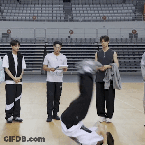 A Man Is Doing A Handstand On A Basketball Court In Front Of Empty Seats GIF
