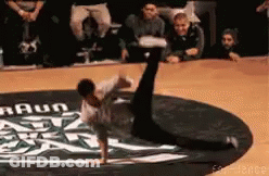 A Man Is Doing A Handstand On A Dance Floor With A Braun Logo In The Background GIF