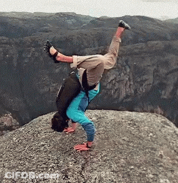 A Man Is Doing A Handstand On A Rocky Cliff . GIF