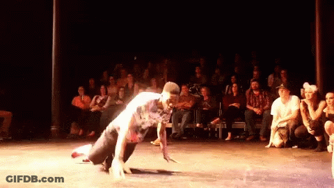 A Man Is Doing A Handstand On A Stage In Front Of A Crowd GIF