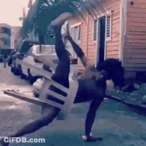 A Man Is Doing A Handstand With A Chair Around His Neck . GIF