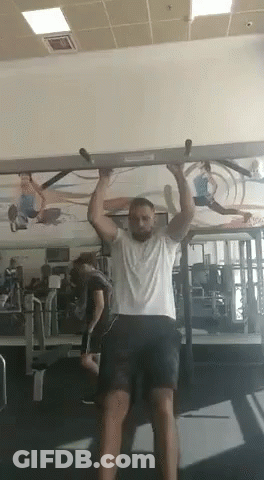 A Man Is Doing A Pull Up Exercise In A Gym . GIF