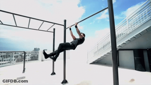 A Man Is Doing A Pull Up On A Bar Outside GIF