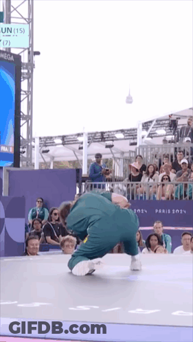 A Man Is Doing A Trick In Front Of A Crowd And A Sign That Says Omega GIF